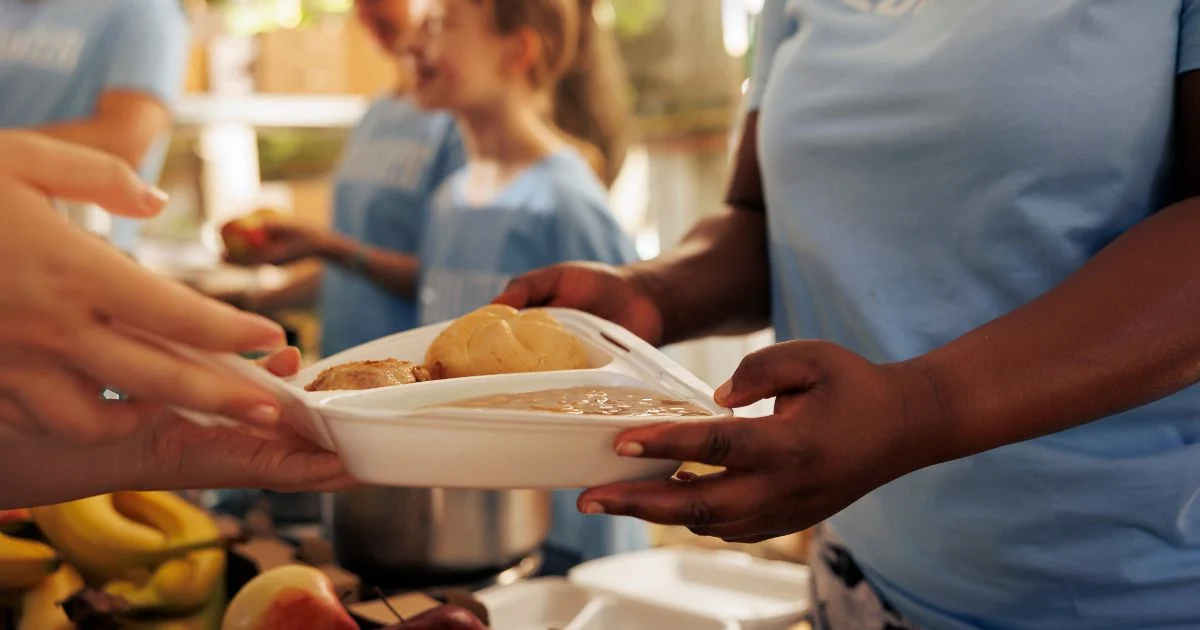 Young woman handing out fresh produce at food drive